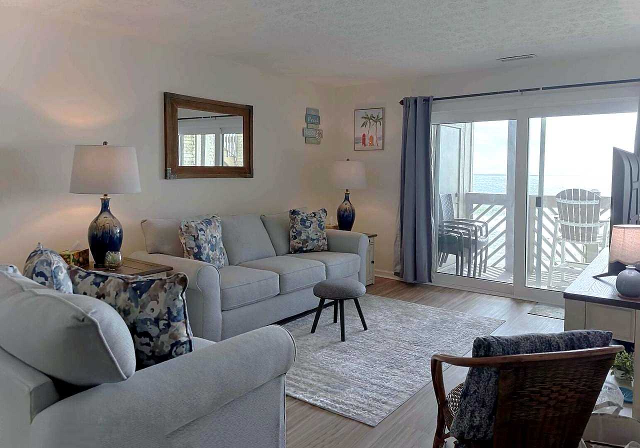Sunlit living room at First Light with oceanfront balcony doors